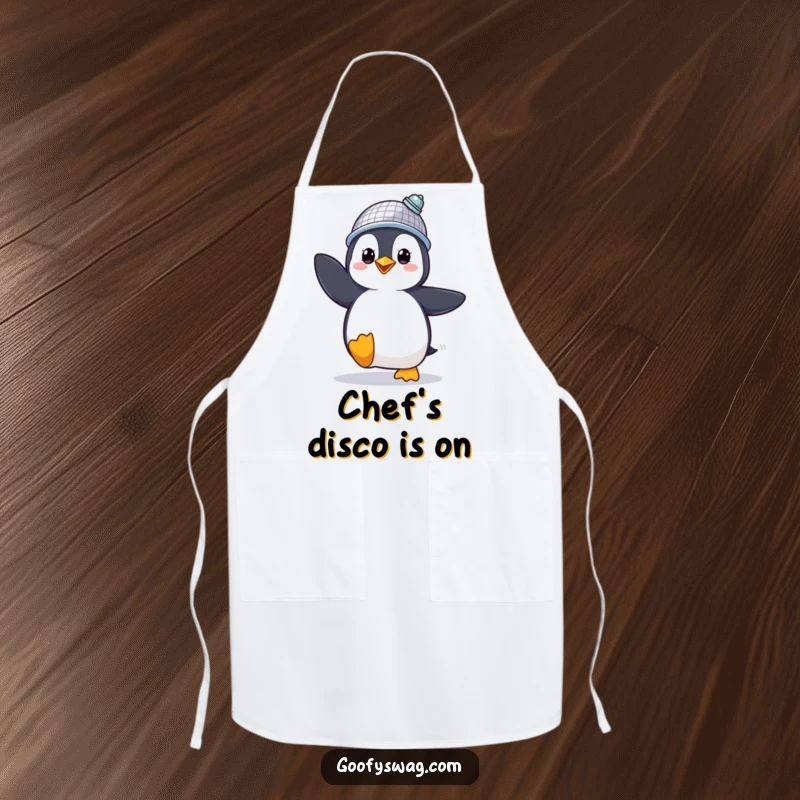 Funny Apron showing a proud penguin in a disco ball hat, dancing energetically, a humorous kitchen accessory.
