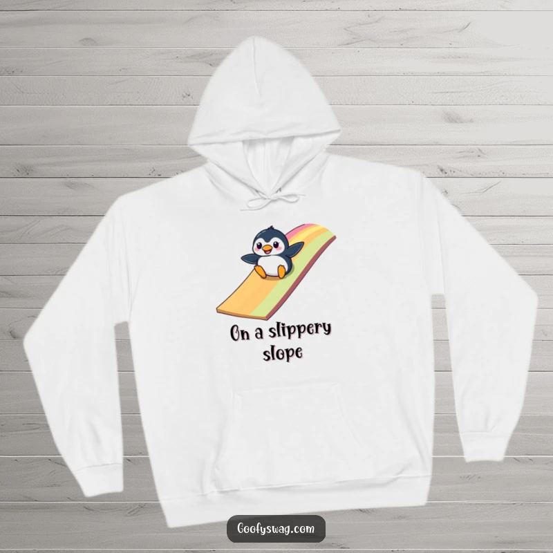 Funny clumsy penguin sliding down a vibrant rainbow ramp, a cozy and humorous hoodie perfect for chilly days.